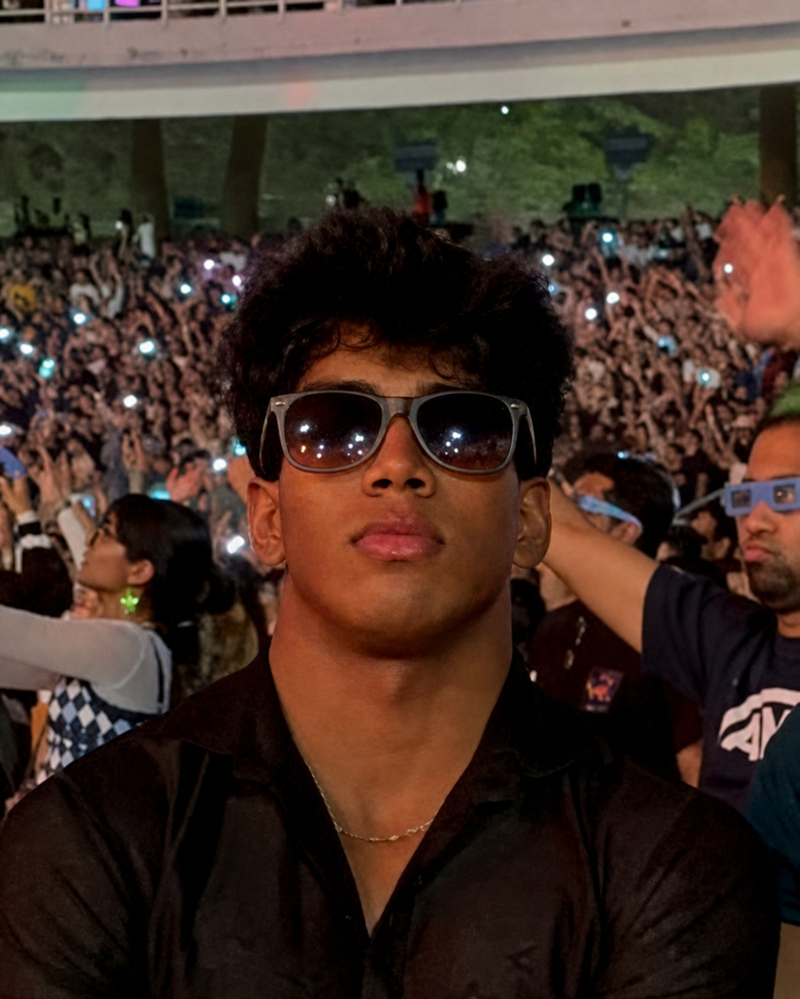 Portrait of Neel Kasar wearing sunglasses at a crowded live event